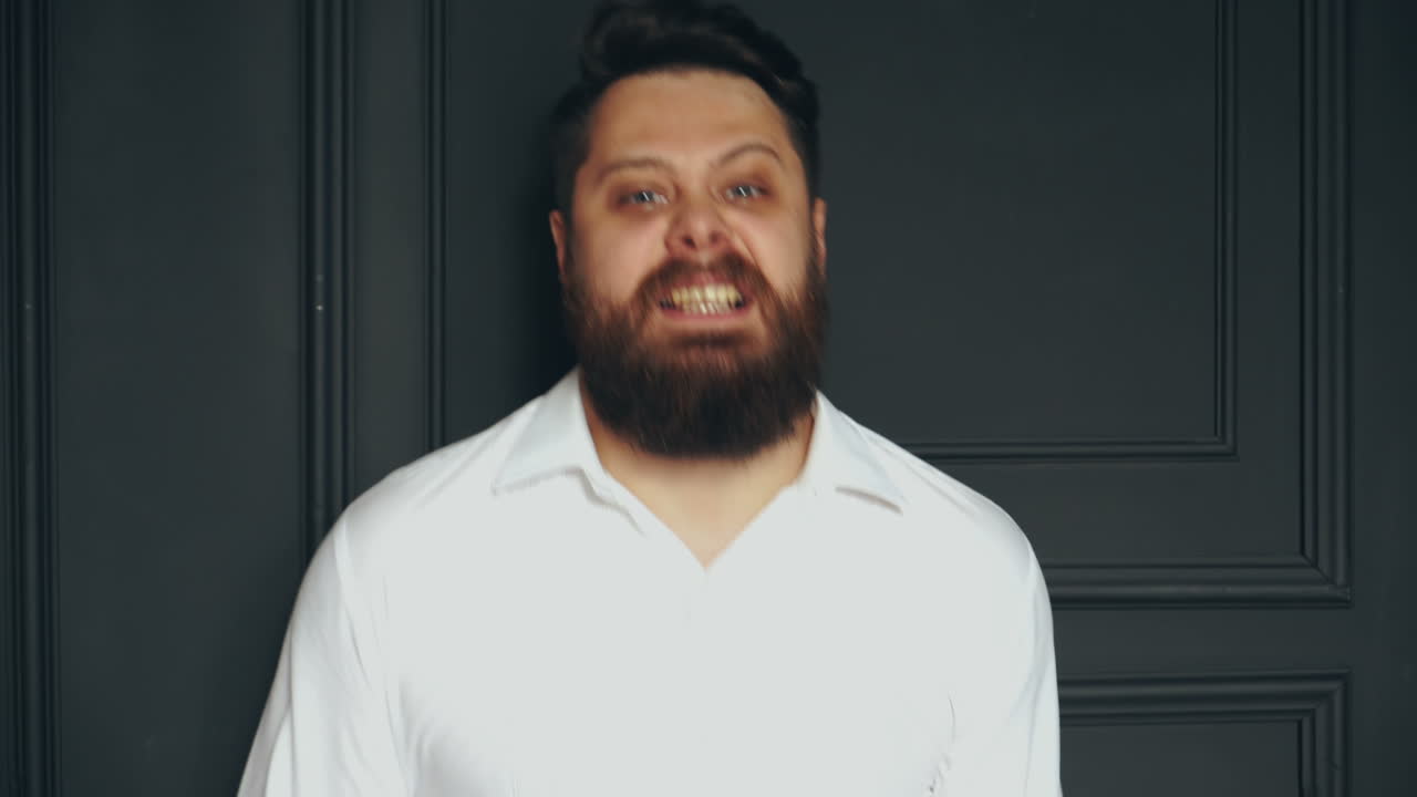 Serious man in studio. Stylish handsome young bearded man in white shirt posing in studio