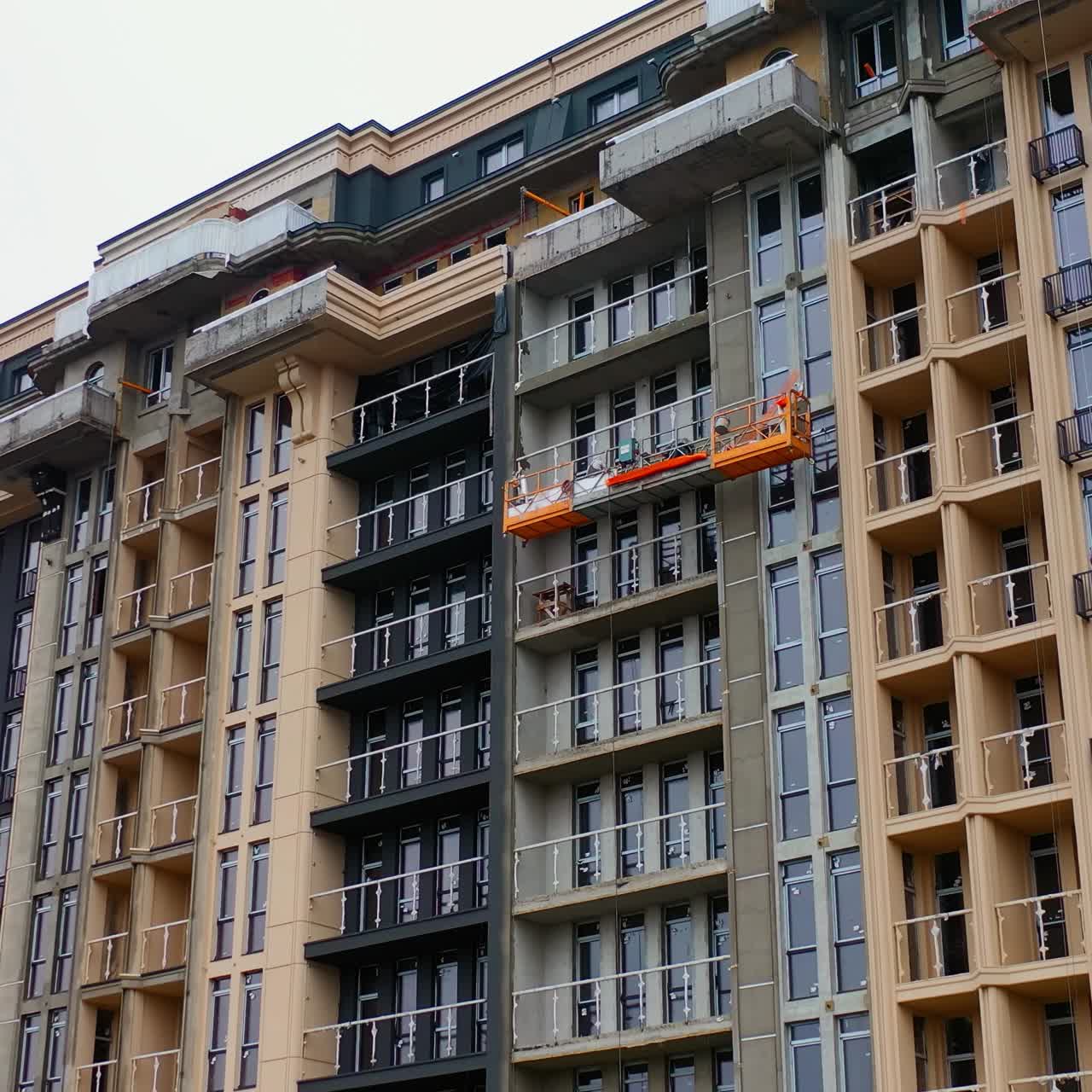 Building of new tower architecture. Modern multi storey building under construction. Front view of a high-rise building. Workers build the tall house.