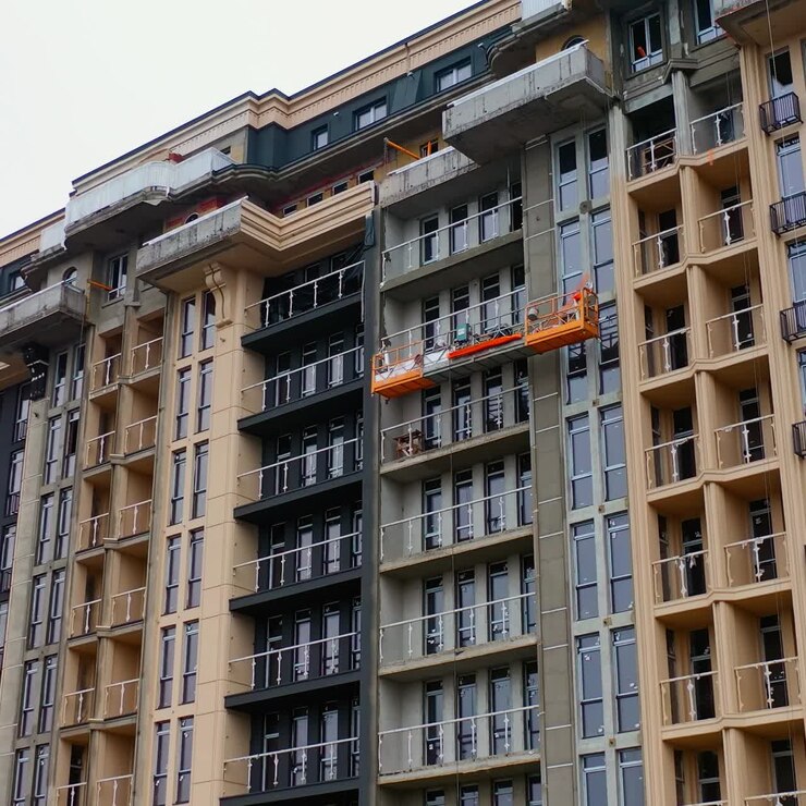 Building of new tower architecture. Modern multi storey building under construction. Front view of a high-rise building. Workers build the tall house.