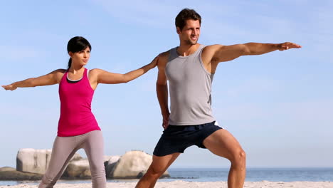 hombre y mujer entrenando en la playa.