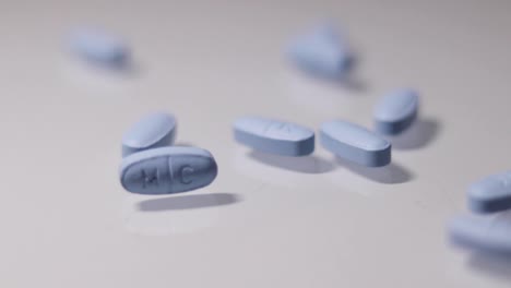 blue pills being thrown onto a white reflective surface in slow motion