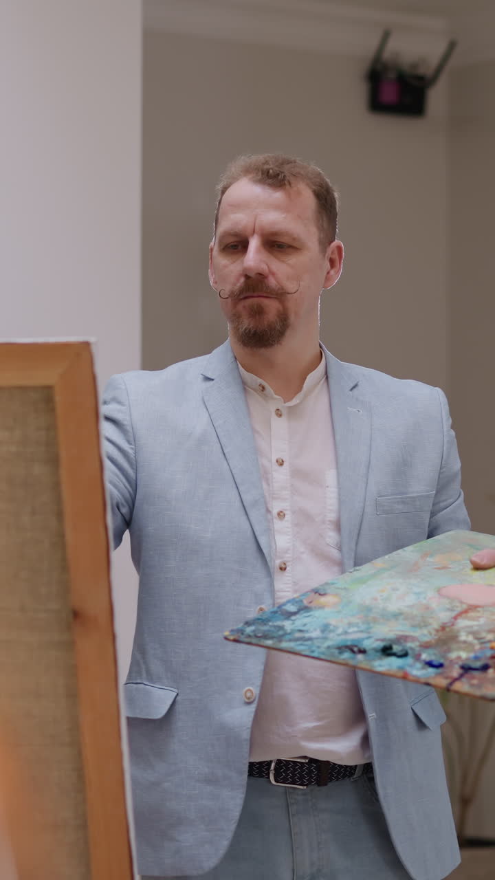 Artist looks at model drawing portrait in studio. Bearded art master holds color slab and woman adjusts hair in residence. Creating beauty in designer studio