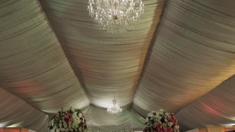 A-wedding-ready-banquet-showcases-top-ceiling-with-hanging-chandelier-and-a-picturesque-view-of-stunning-stage