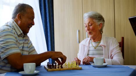 Senior-woman-using-digital-tablet-while-her-friends-playing-chess-4k