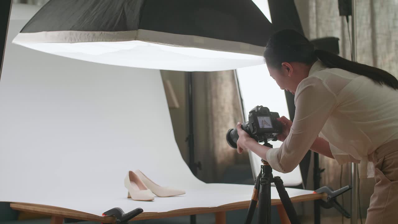 fotógrafa asiática celebra el éxito de tomar fotos de zapatos femeninos en su estudio casero