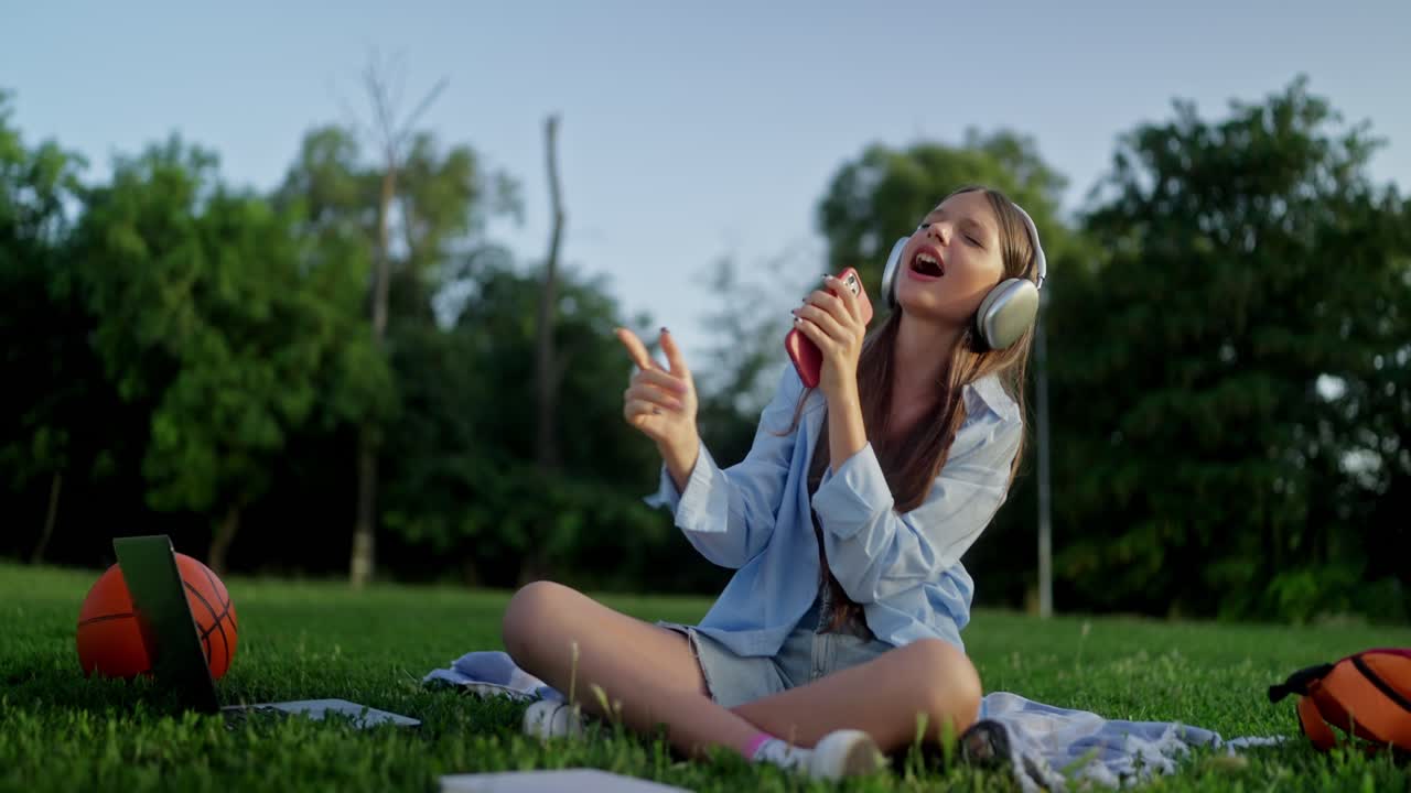 una mujer joven cantando en un parque.