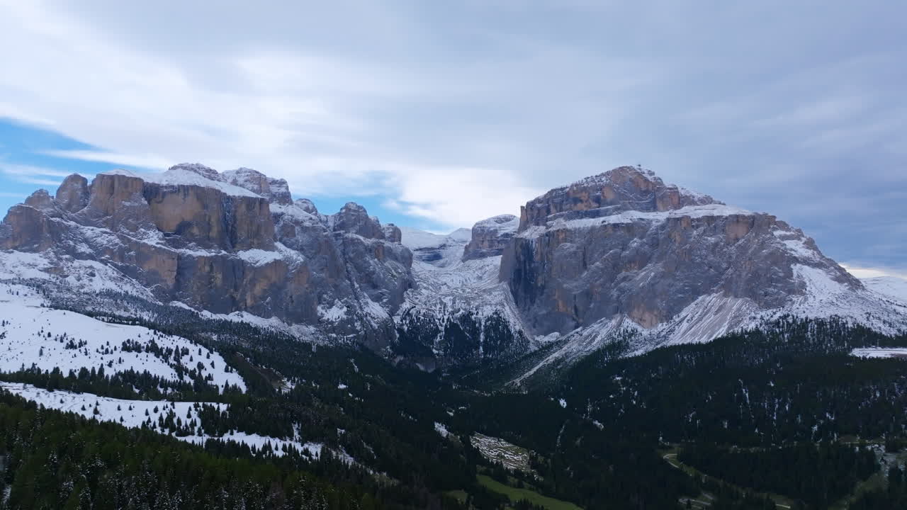 imágenes aéreas girando alrededor de los verdes bosques y montañas cubiertas de nieve de sass pordoi en el norte de italia.
