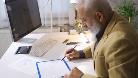 Mature-businessman-drawing-and-analyzing-financial-growth-graph-in-his-office.