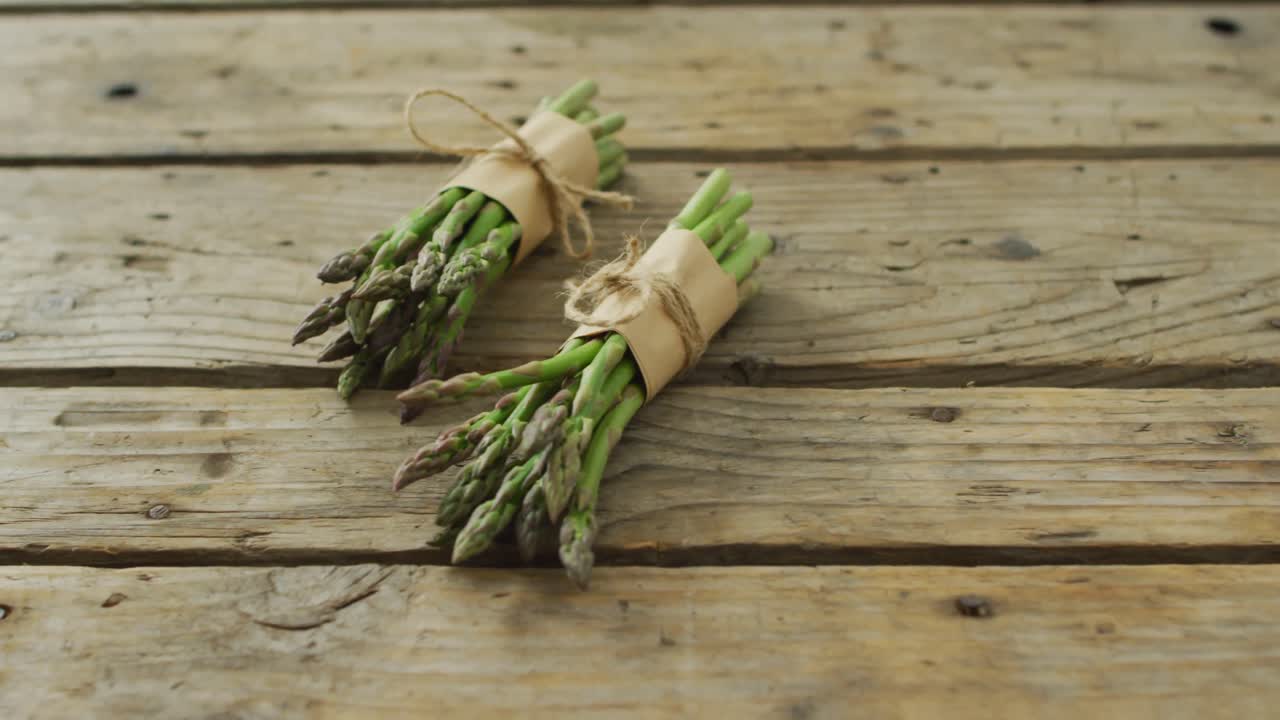 Video di due mazzetti di asparagi freschi su sfondo di legno
