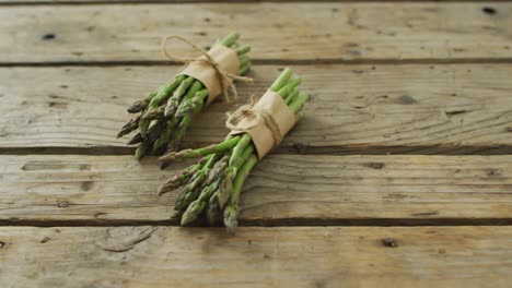 video of two fresh asparagus bundles on wooden background