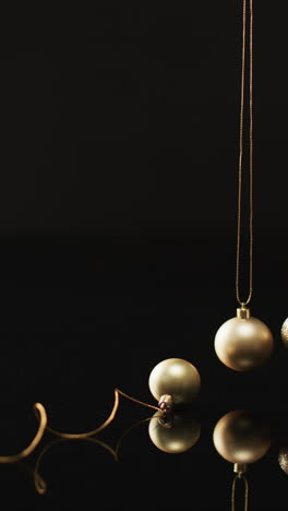 vertical video of gold baubles christmas decorations and copy space on black background