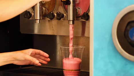 pouring a pink slushy into a cup