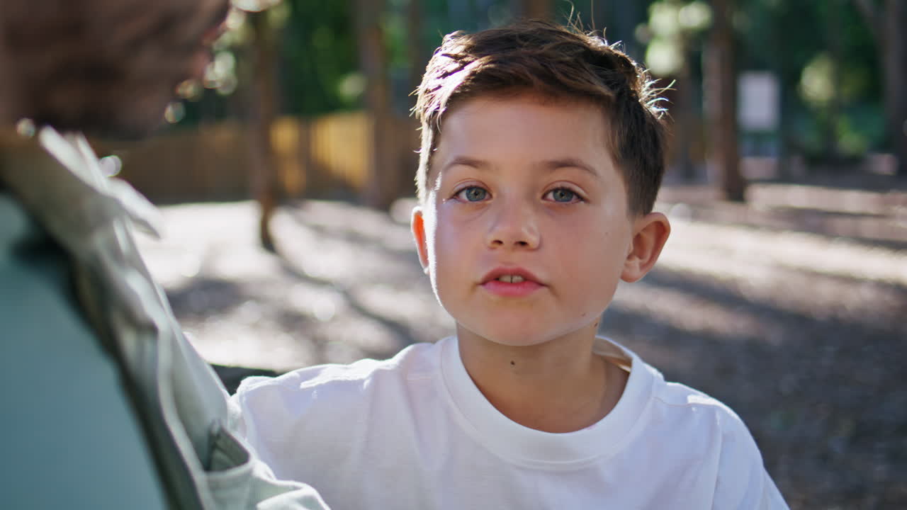 Smiling boy talking father joyful moment at sunny park closeup. Kid man speaking