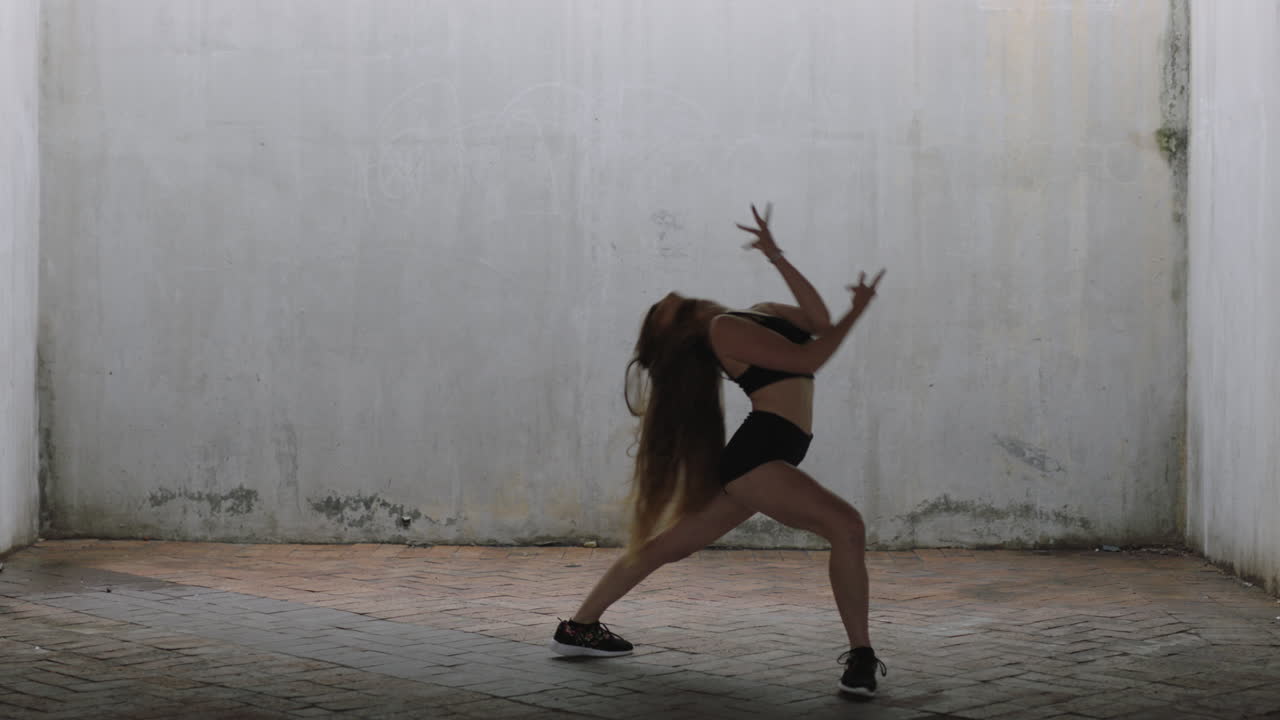 mujer bailarina hermosa joven bailarina de calle caucásica realizando movimientos contemporáneos disfrutando de la expresión de la danza moderna practicando en un almacén grungy