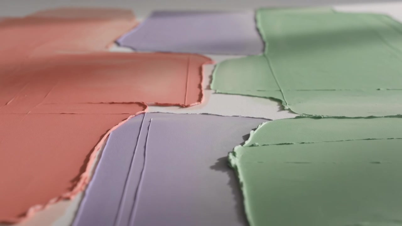 Pulling camera back revealing four pastel paint swatches on white surface, showing textured edges