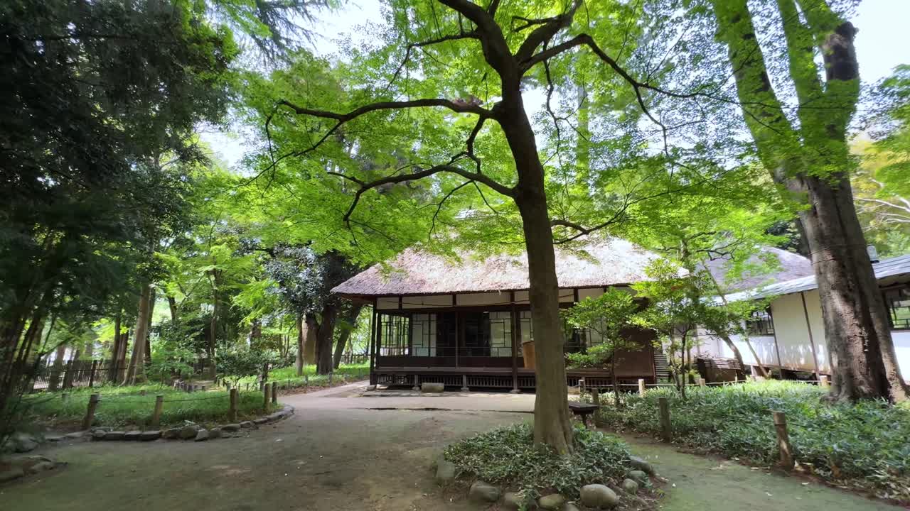 A peaceful and scenic view of Roka Kosyuen Park in Tokyo, Japan, featuring lush greenery and traditional architecture