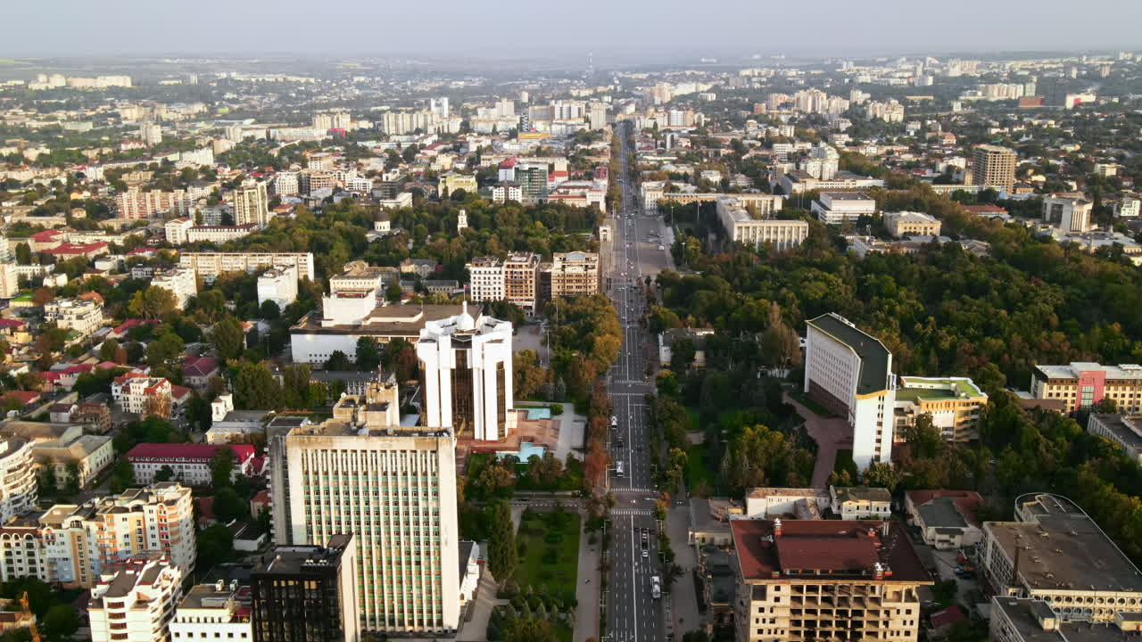 Aerial drone view of Chisinau downtown. Panorama view of multiple buildings, Parliament, Presidency, roads with moving cars and lush trees. Sunset. Moldova