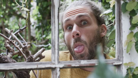 portrait of happy caucasian man making faces in garden, slow motion