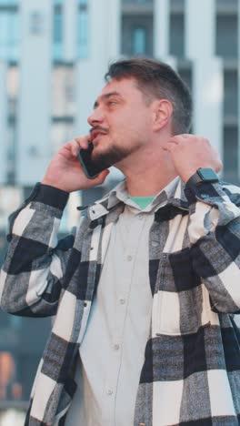 Caucasian mature man tourist arguing talking on smartphone while walking in downtown city street