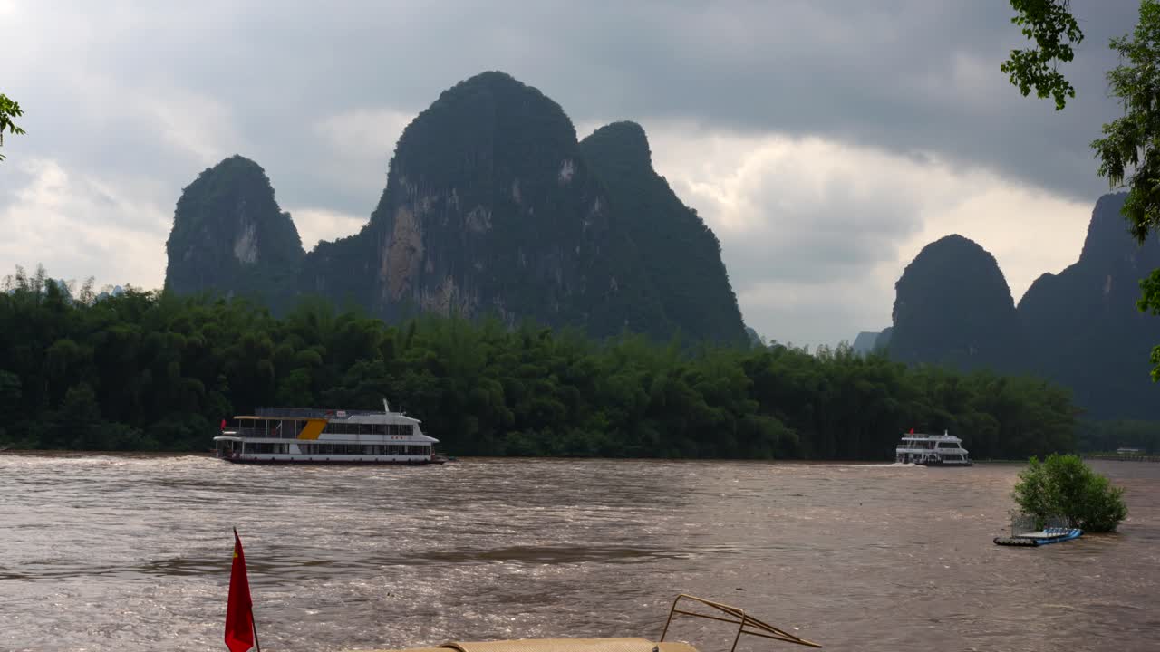크루즈는 핑의 리 강을 항해합니다. 중국의 구름이 많은 날 배경에 카르스트 산맥이 있습니다.