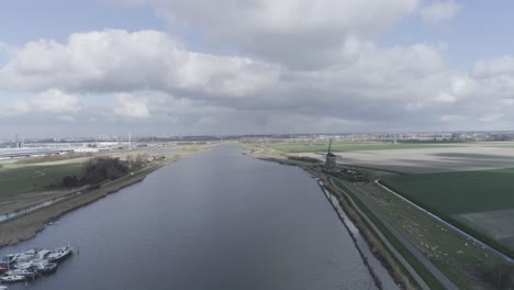 Forward-Drone-shot-of-Dutch-landscape-with-sheep,-windmills-and-small-harbor