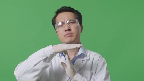 close up of upset asian man scientist shaking his head and doing time out gesture with hands while standing on the green screen background in the laboratory