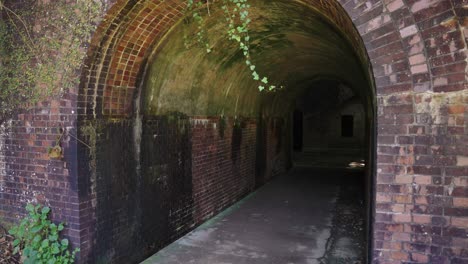 decaying tunnel of red brick tomogashima military fort, japan