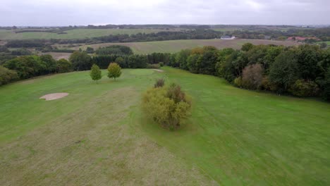 vista aérea de un campo de golf con dos personas caminando junto a un carro de golf