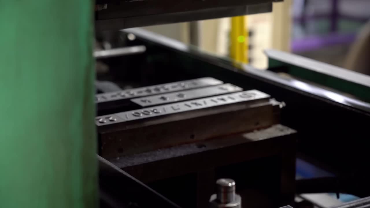 A metal stamping machine presses identification numbers into the drum lids