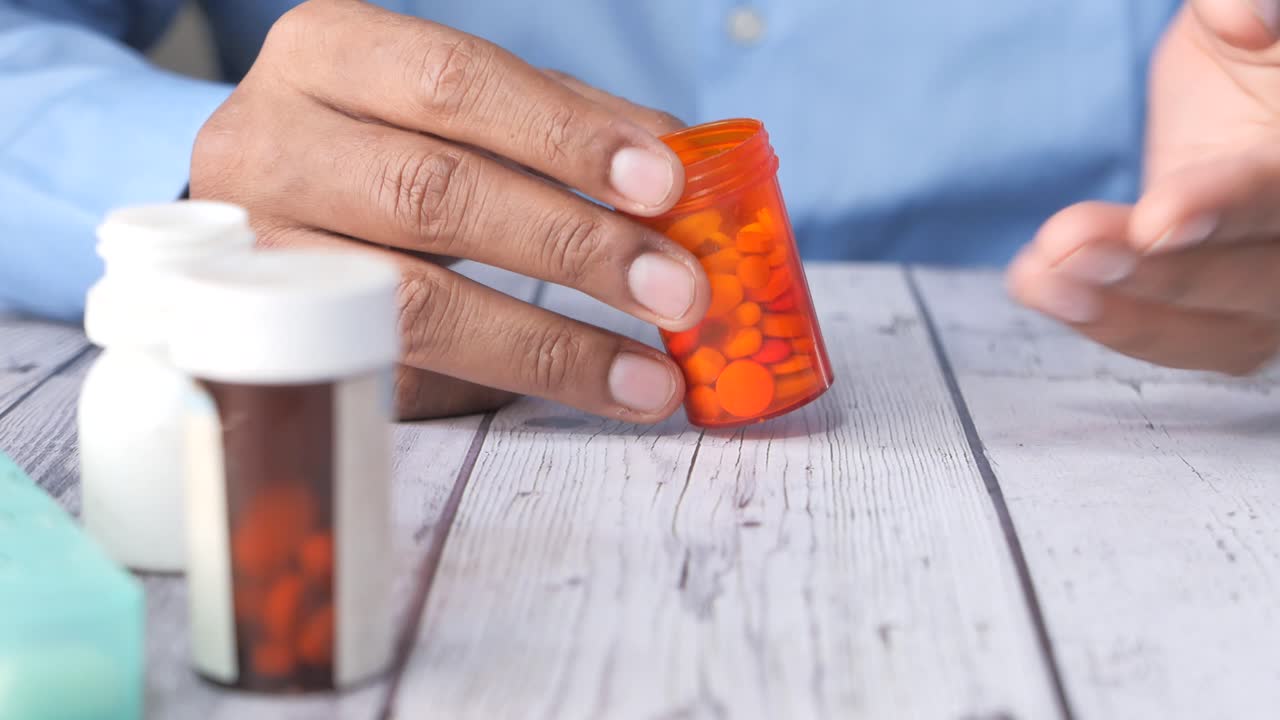 persona que sostiene frascos de pastillas y pastillas