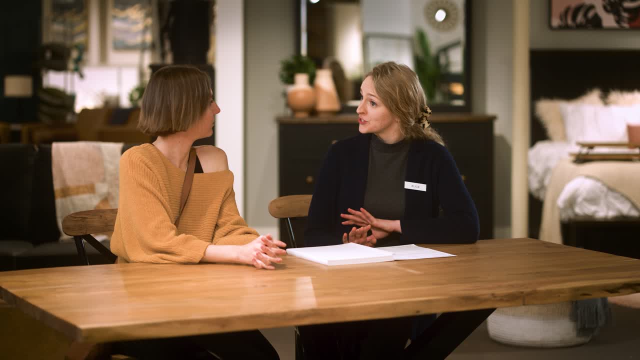 Kunde og sælger bliver enige om en aftale, mens de sidder sammen ved et spisebord.