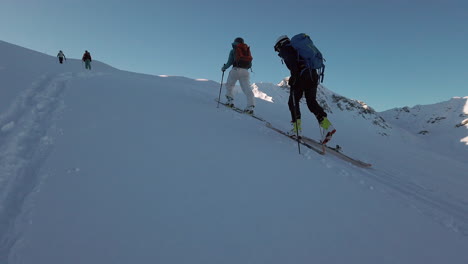 A-small-group-of-young-cross-country-skiers-ascending-a-peak-in-the-Montafon-range-Austrian-Alps,-slow-motion