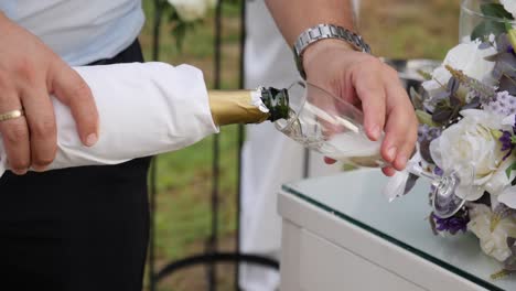 Primer-Plano-En-Cámara-Lenta-De-Manos-Masculinas-Sirviendo-Champán-Al-Aire-Libre-En-Una-Recepción-De-Bodas-Mientras-Se-Toman-Fotografías