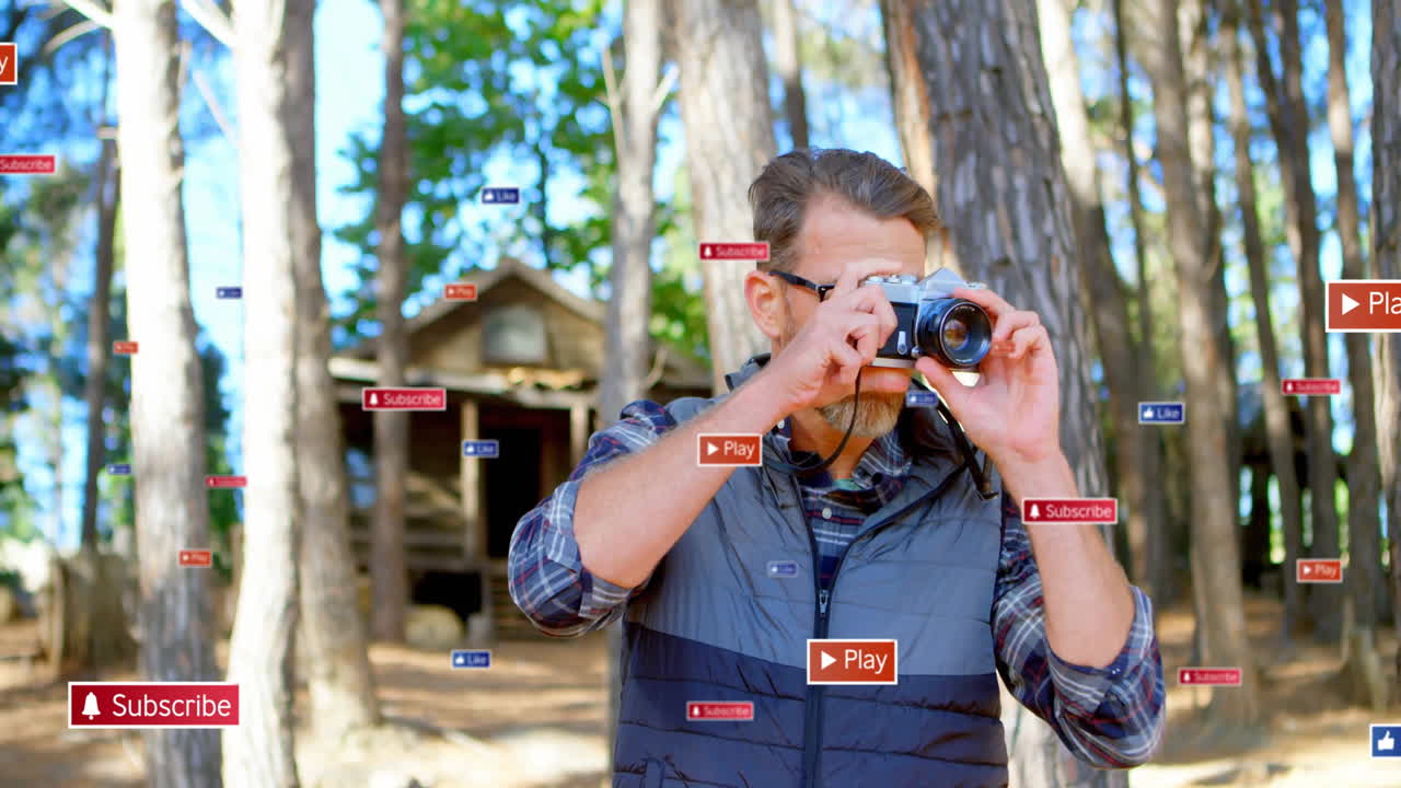 man holding camera standing in forest, with social media subscribe play like icons floating around