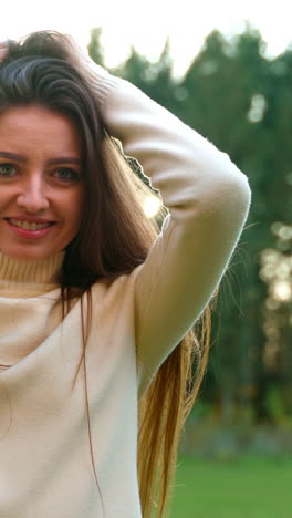 smiling caucasian lady in warm white sweater touching and waving her long hair. good time spent outdoors in autumn park.