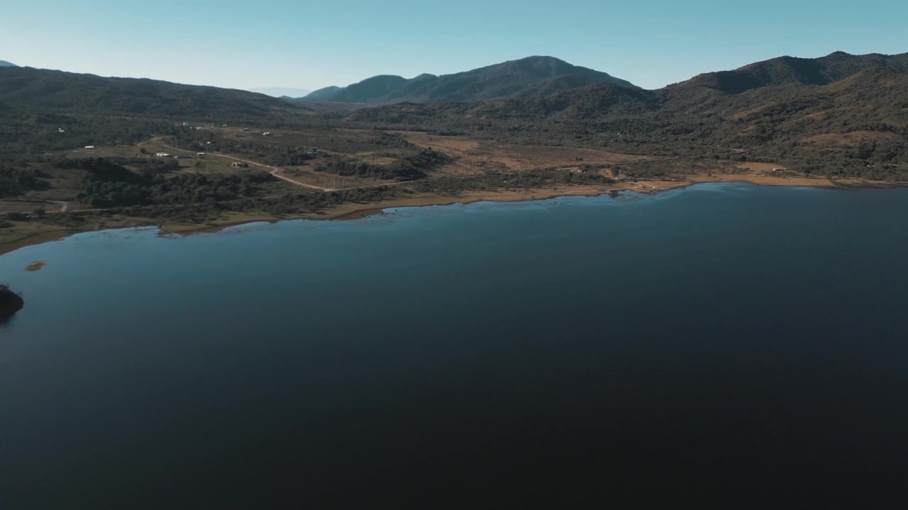 Luftoptagelse over et roligt reservoir, der følger en barsk bjergkystlinje