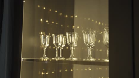 close-up view of several empty crystal glasses on wooden table, reflected christmas lights