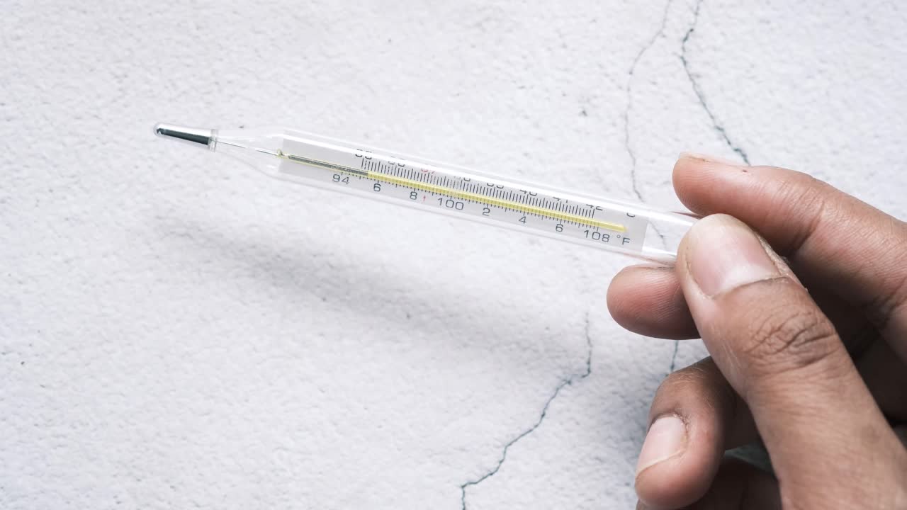유리 수은 온도계를 들고 있는 손