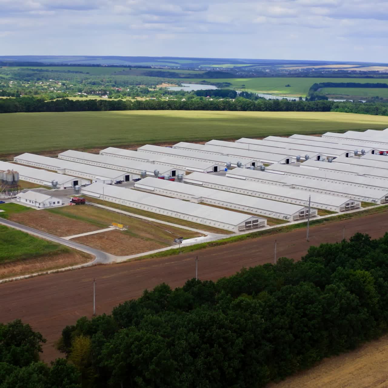 Large farm in rural place in summer. Modern agricultural buildings surrounded by amazing nature in the countryside. Aerial view