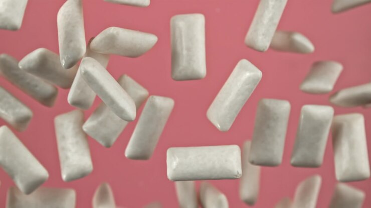 Pezzi di gomma da masticare bianca che cadono in super slow motion su sfondo rosa