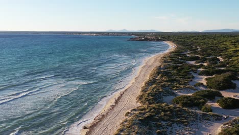 trench beach at the southern edge of mallorca island in spain with people walking on sand, aerial flyover reveal shot