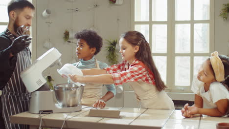 girl putting ingredients in mixer bowl during cooking class with chef