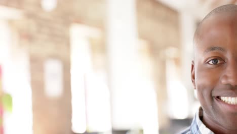 Portrait-of-happy-african-american-casual-businessman-in-creative-office-in-slow-motion