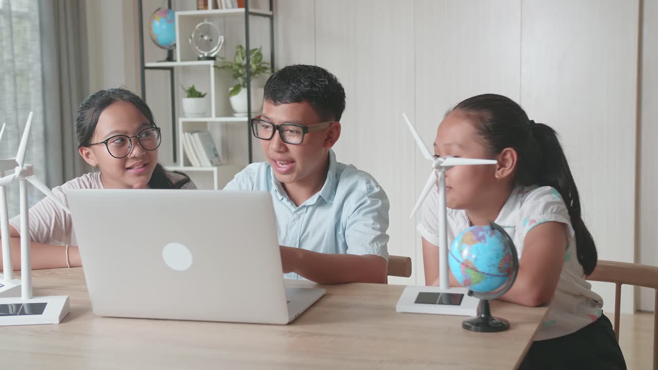 Class Of Smart Young Asian Children Work As A Team Using Laptop Computers To Program Wind Turbines. Classroom With Kids Learning About Eco-Friendly Forms Of Renewable Energy