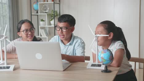 class of smart young asian children work as a team using laptop computers to program wind turbines. classroom with kids learning about eco-friendly forms of renewable energy