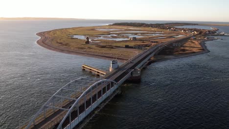 las imágenes aéreas de drones capturan un puente impresionante que se extiende sobre el vasto paisaje marítimo en islandia durante el día, con una estructura graciosamente arqueada sobre el agua brillante debajo.