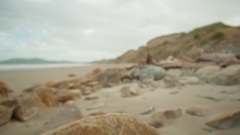 rising revealing shot of a rocky beach with a boulder in the foreground in new zealand