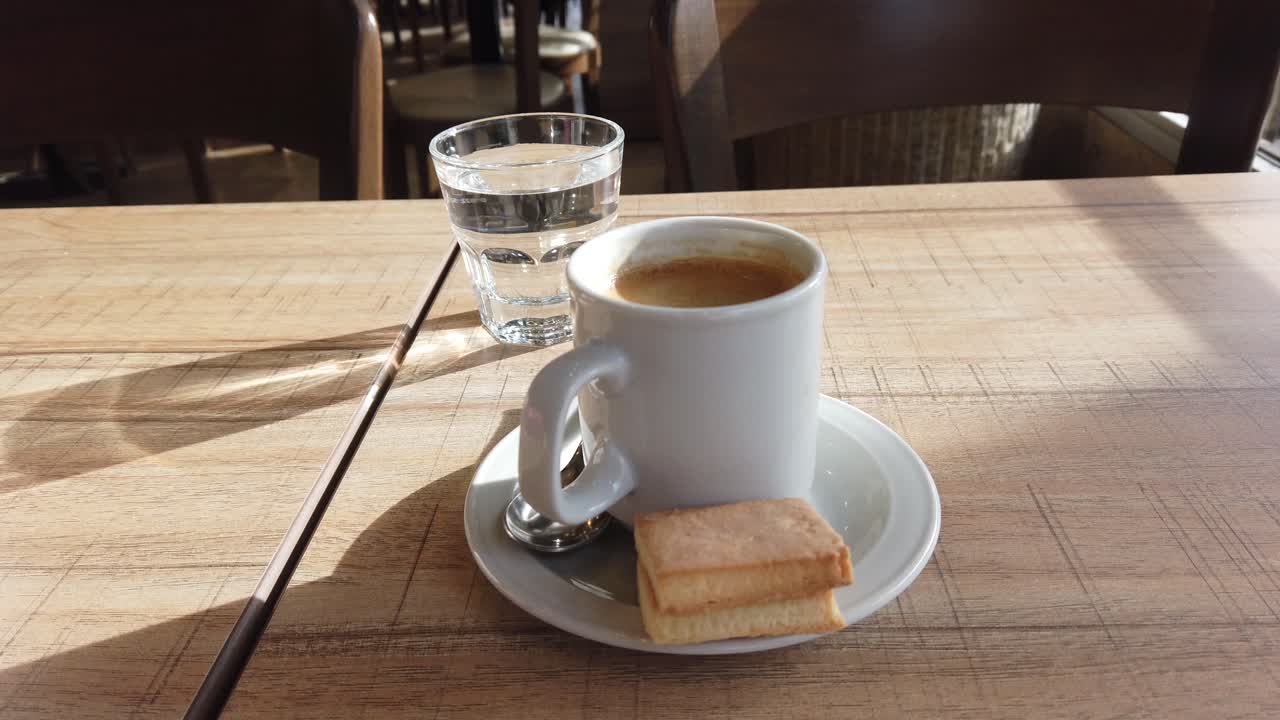 Close up of espresso coffee mug with biscuits in Italian style restaurant table, morning daylight