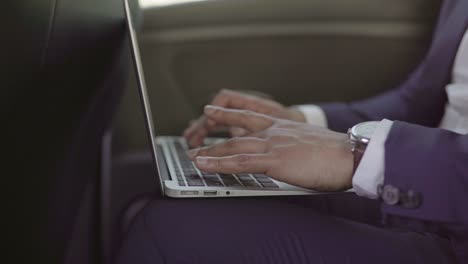 partial view of businessman using laptop in car