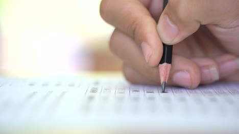 examination test concept, close up pencil on test answer paper, pencil on hand of student in examination classroom. it multiple choice for assessment of knowledge evaluation graduate education